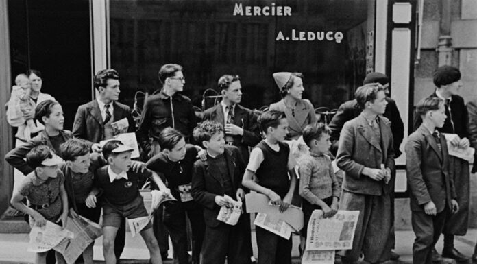 Il Tour de France di Robert Capa e altri fotografi della Magnum A crowd gathered in front of Mr. Pierre Cloarec's bicycle shop, who is racing in the Tour de France. Pleybon, France, 1939 © Robert Capa © International Center of Photography Magnum Photos